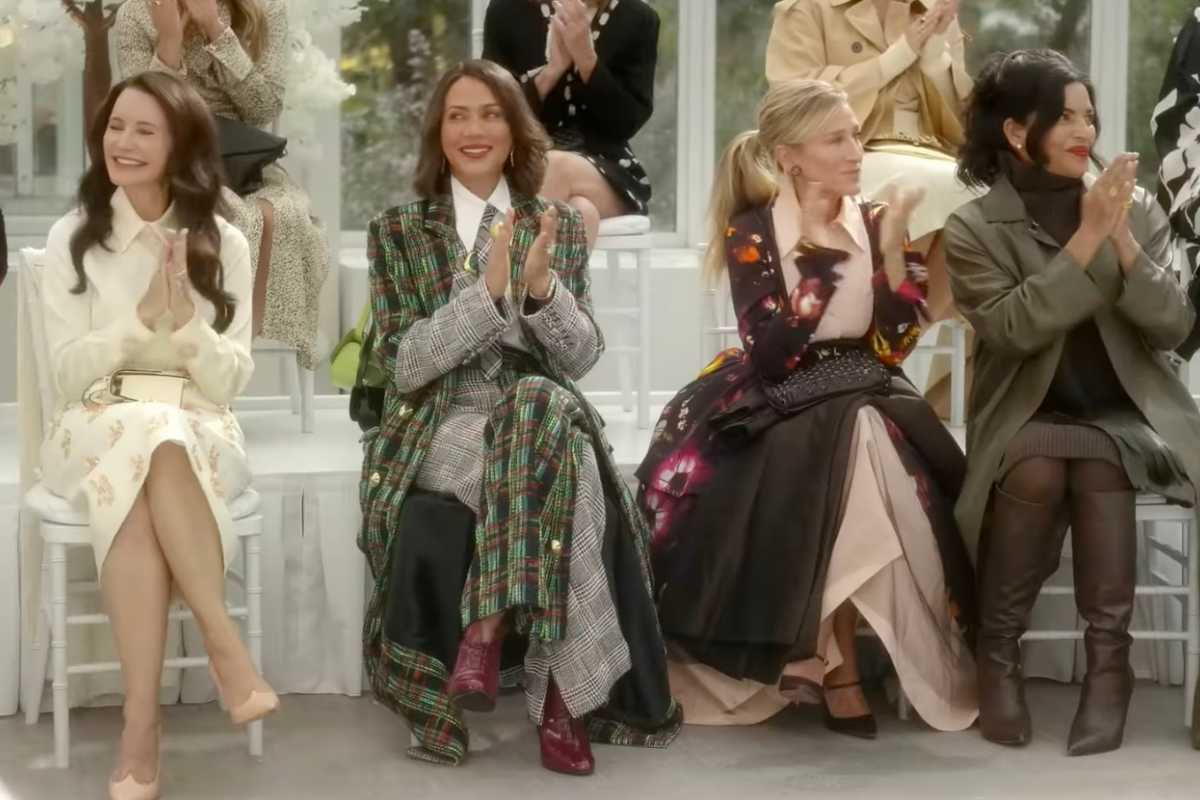 Le protagoniste della serie sedute mentre guardano una sfilata