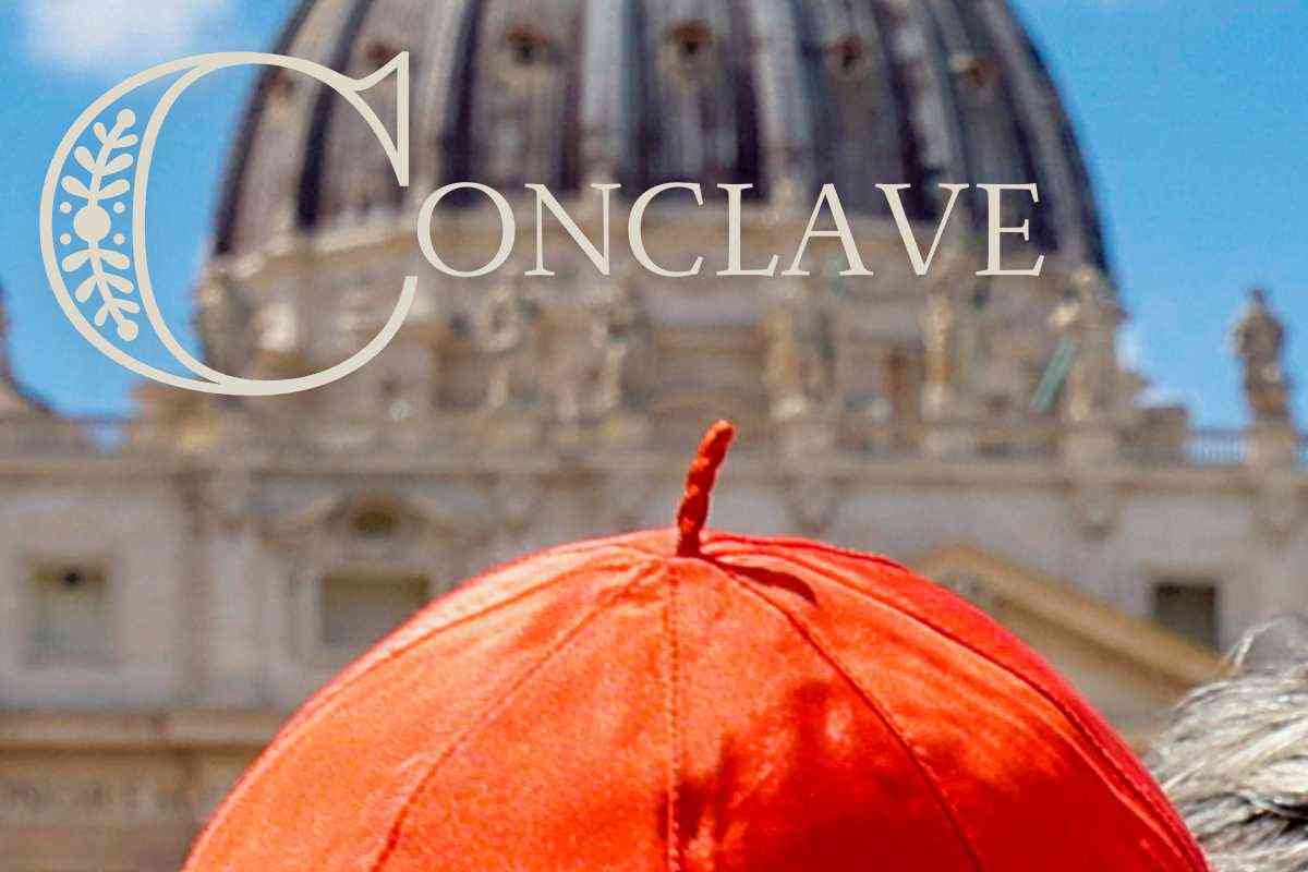 Il cappello di un cardinale e sullo sfondo la scritta Conclave con dietro la Cupola del Vaticano
