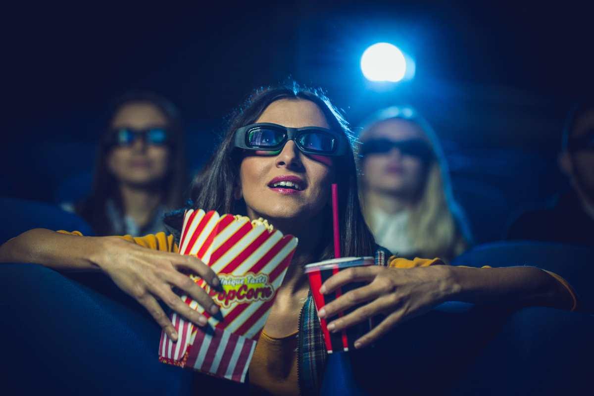 Ragazza al cinema con gli occhiali 3D e i pop corn in mano