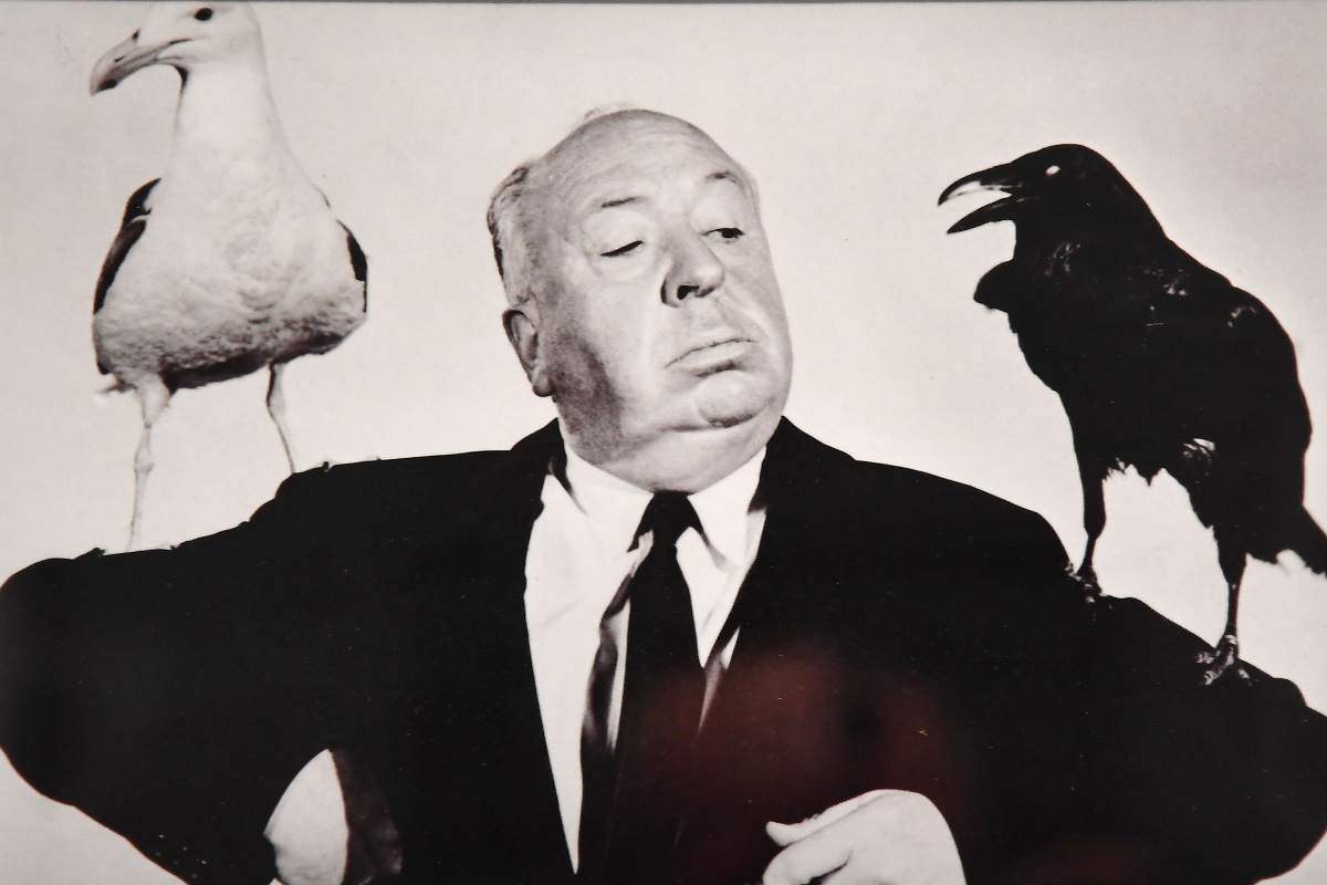 Alfred Hitchcock con due grossi uccelli sulle spalle