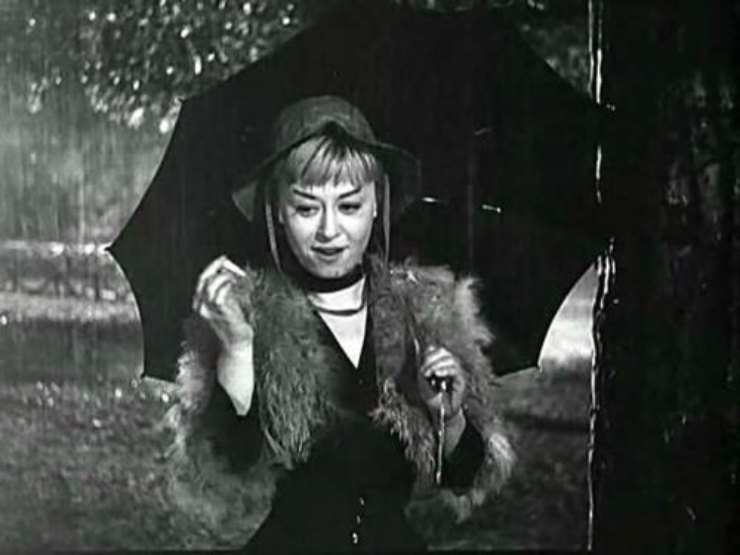 Giulietta Masina sotto un ombrello in una scena del film Le notti di Cabiria