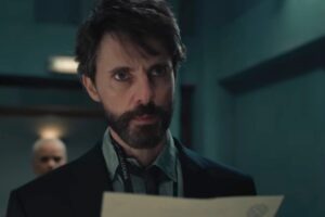 Matthew Gode in una scena di Dept Q con un foglio in mano