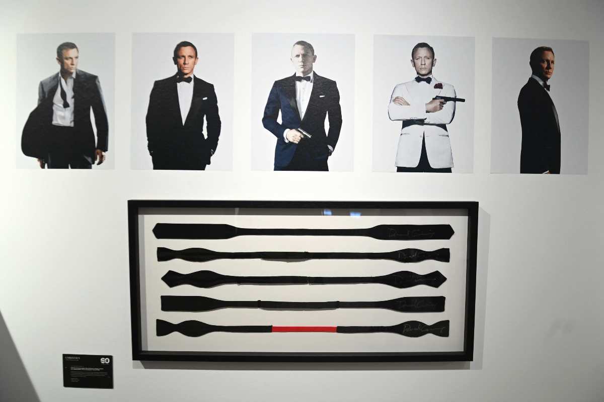 Un cartellone bianco con delle foto di Daniel Craig e i vari papillon