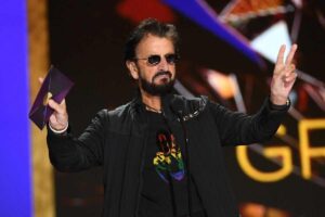 Ringo Starr con le braccia spalancate parla al microfono