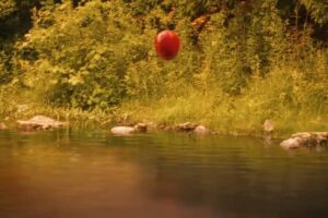 Un palloncino rosso in volo sopra un fiume