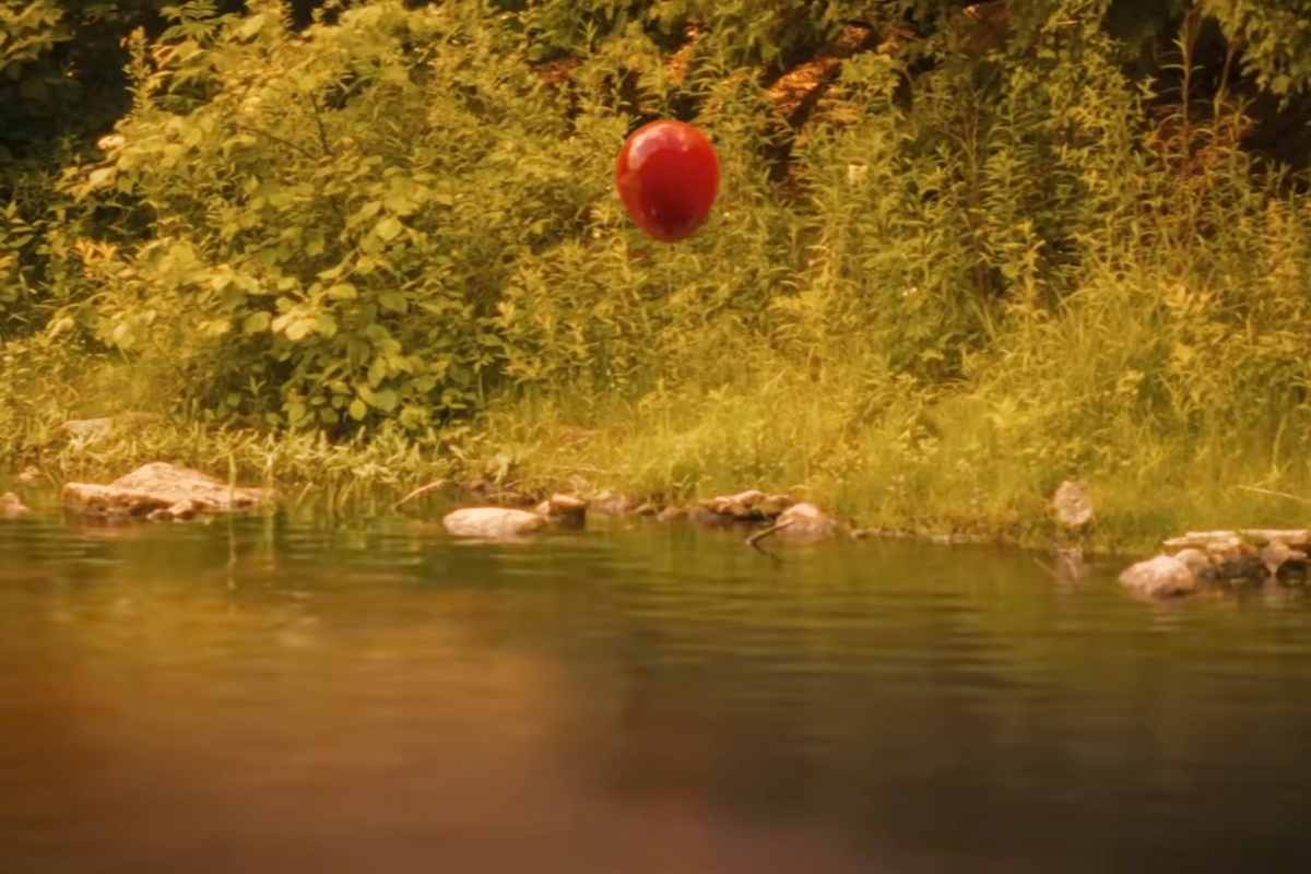 Un palloncino rosso in volo sopra un fiume