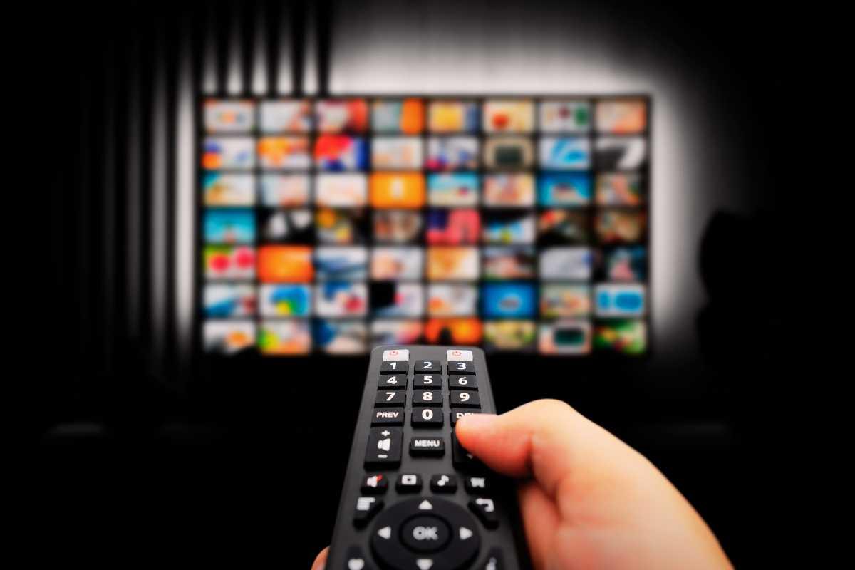 Telecomando con televisore sullo sfondo pieno di opzioni streaming