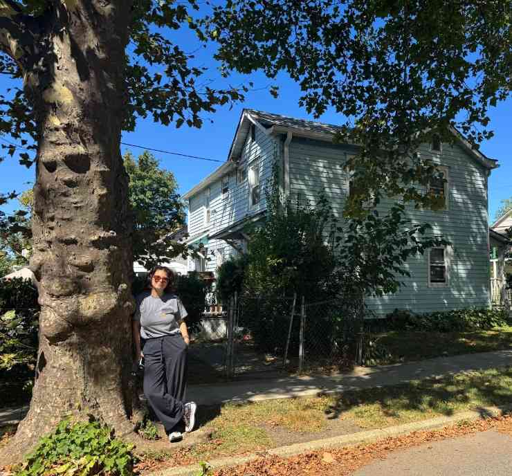 Una donna appoggiata ad un albero di fronte alla casa di Bruce Springsteen a Freehold