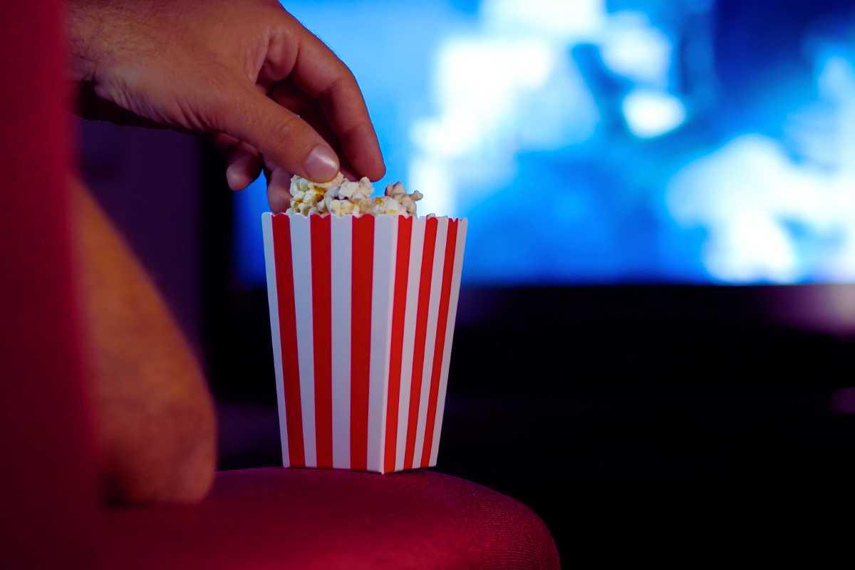 Una mano immersa in una busta di popcorn