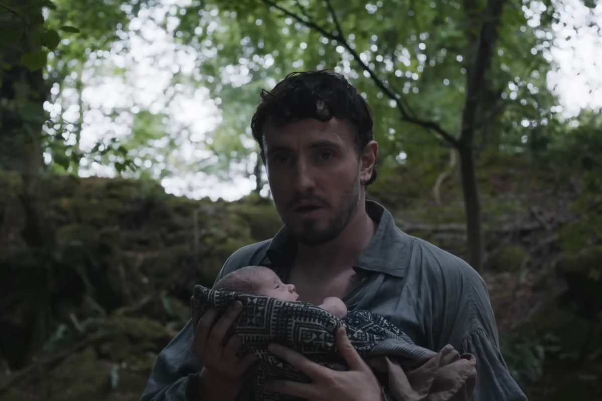 Paul Mescal in una scena del film Hamnet con un bambino in braccio