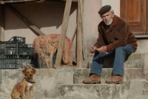 Un'immagine del film, Efisio seduto sulle scale insieme a lui un cane
