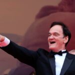 Quentin Tarantino esulta con il braccio leggermente sollevato e due dita a vittoria