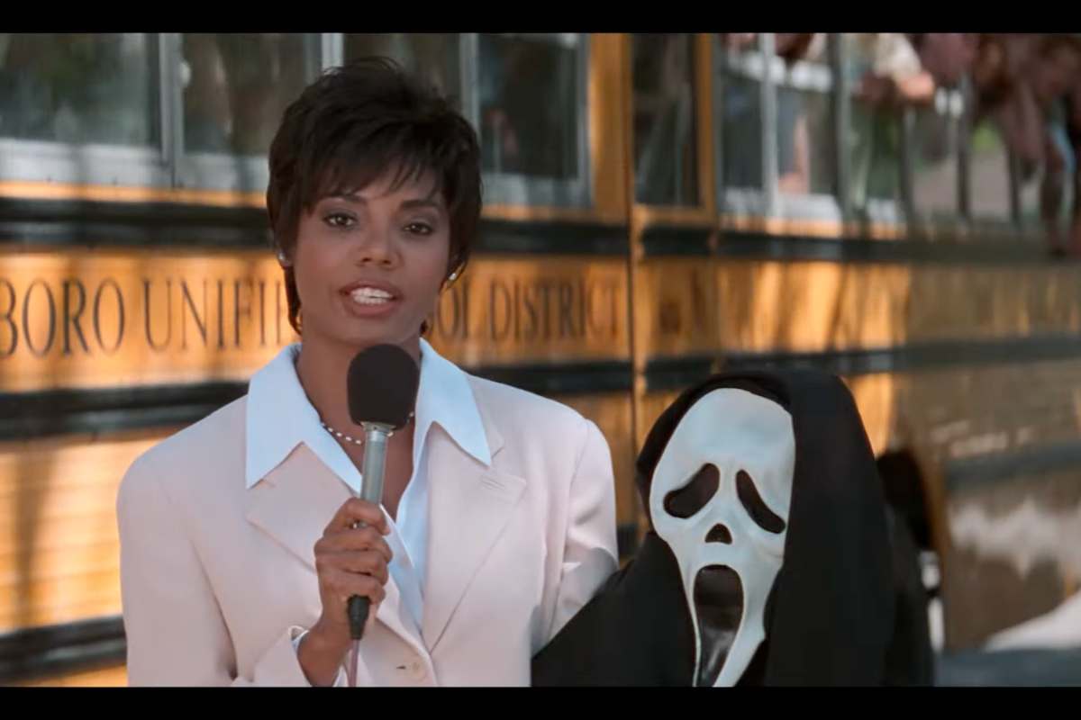 Una scena del film Scream 1, una giornalista con in mano la maschera del killer