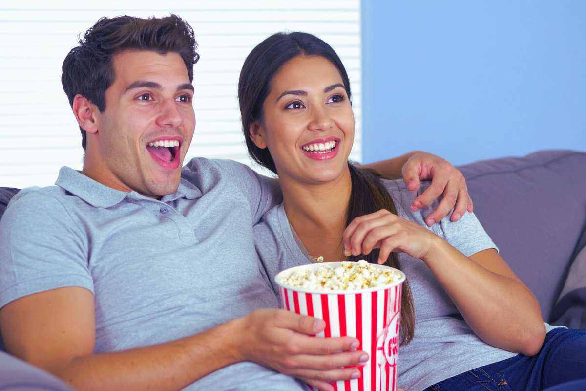 Uomo e donna con busta di pop corn guardano un film