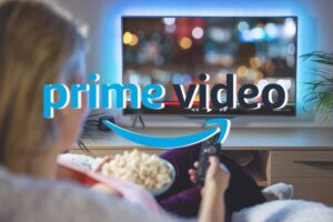 Persona con telecomando in mano di fronte la tv e logo Prime Video