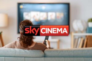 Persona seduta sul divano che guarda la tv e logo Sky Cinema
