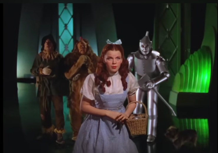 Una scena del film Il mago di Oz con Dorothy e alle sue spalle il leone l'uomo di latta e lo spaventapasseri