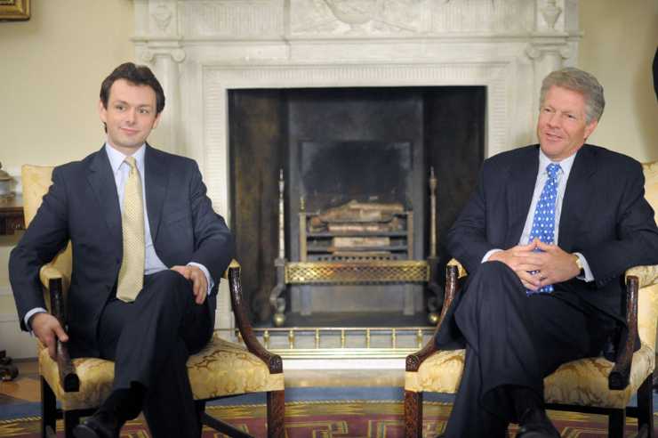 Michael Sheen in una scena del film Frost / Nixon seduto sulla sedia con dietro un camino