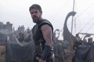 Matt Damon indossa l'armatura e veste i panni di Ulisse, alle sue spalle si intravede un pezzo di imbarcazione