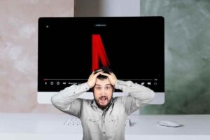 Uomo disperato con le mani sulla testa e logo netflix che si forma sullo schermo di un computer