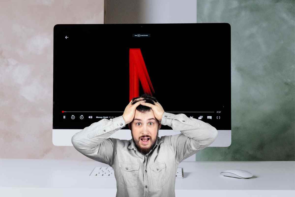 Uomo disperato con le mani sulla testa e logo netflix che si forma sullo schermo di un computer