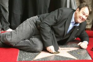 Dan Aykroyd sdraiato sulla Walk of Fame di Los Angeles durante lo svelamento della stella dedicata a John Beluschi