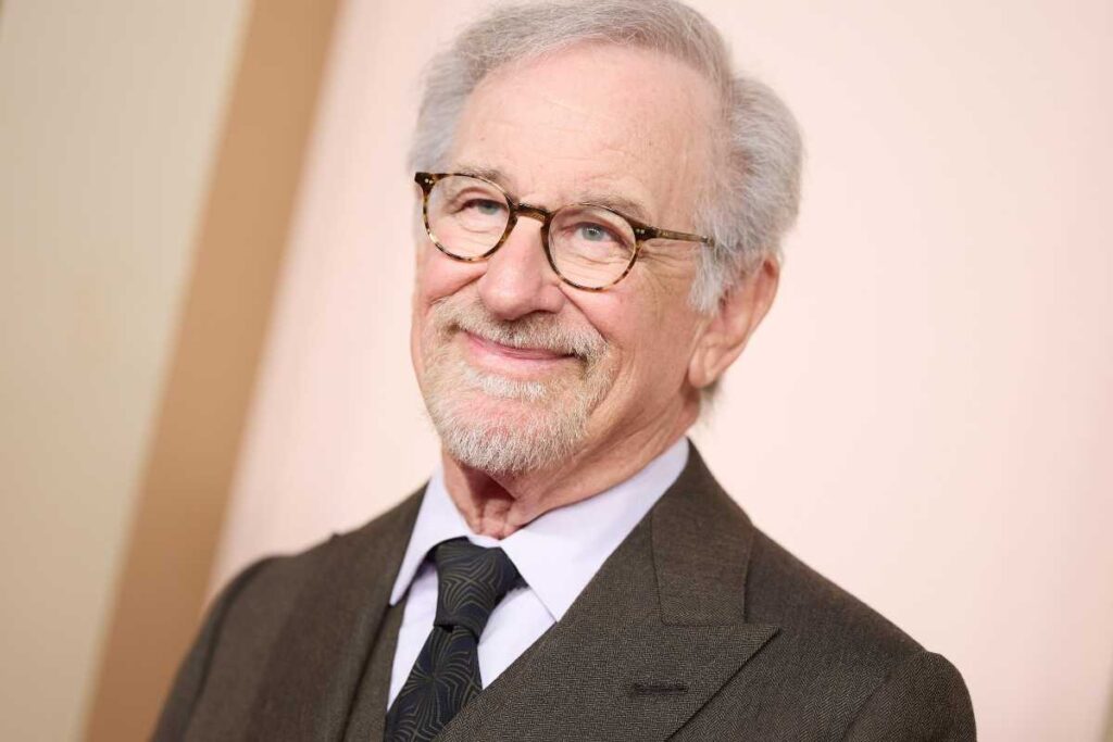 Steven Spielberg in posa vestito elegante accenna un sorriso