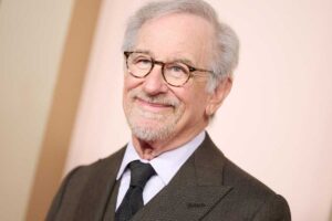 Steven Spielberg in posa vestito elegante accenna un sorriso
