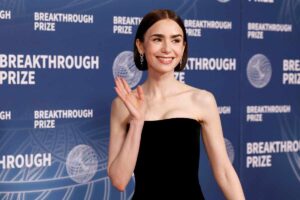 Lily Collins mezzo busto saluta con la mano destra i fotografi