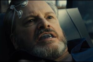 Colin Firth con degli elettrodi attaccati alla fronte e un proteggi denti