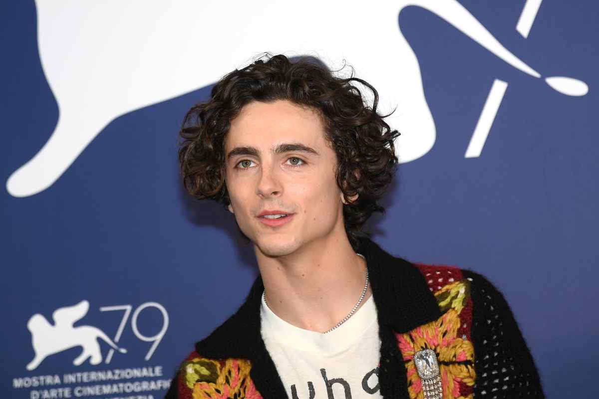 Timothee Chalamet sullo sfondo il cartello del Leone di Venezia