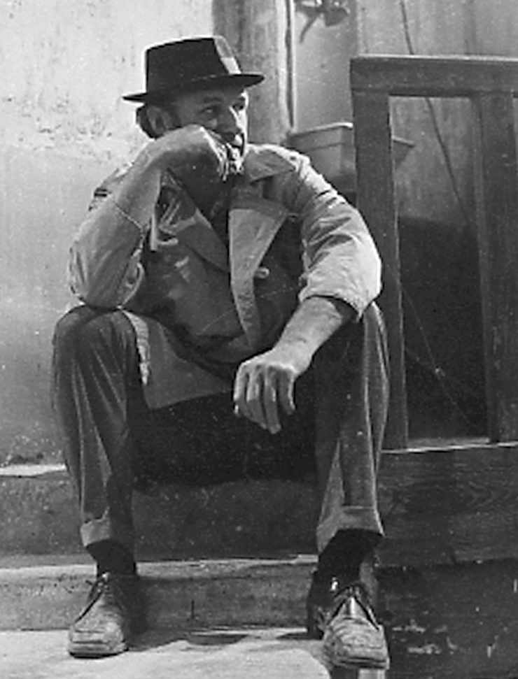 Gene Hackman da giovane seduto su uno scalino con un cappello in testa