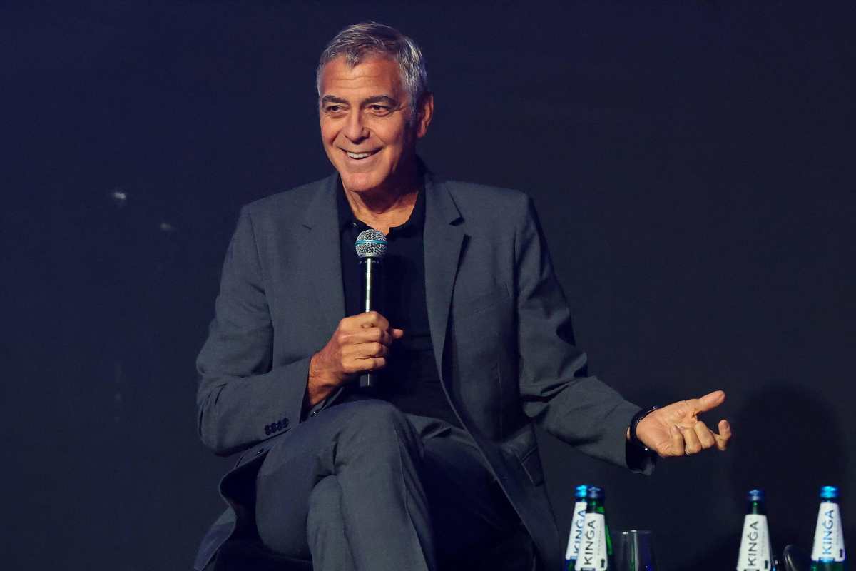 George Clooney parla seduto su una sedia con il microfono in mano