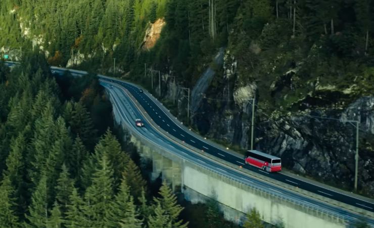 Un paesaggio montano con un bus rosso che percorrere la strada