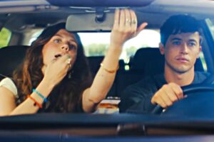 Un uomo e una donna in auto, lei si trucca guardandosi allo specchietto retrovisore