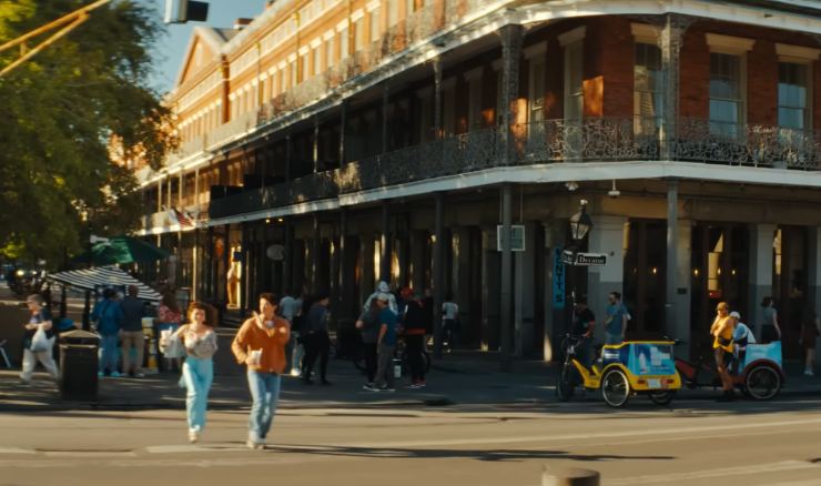 Una via di New Orleans piena di gente, due persone che corrono per attraversare la strada