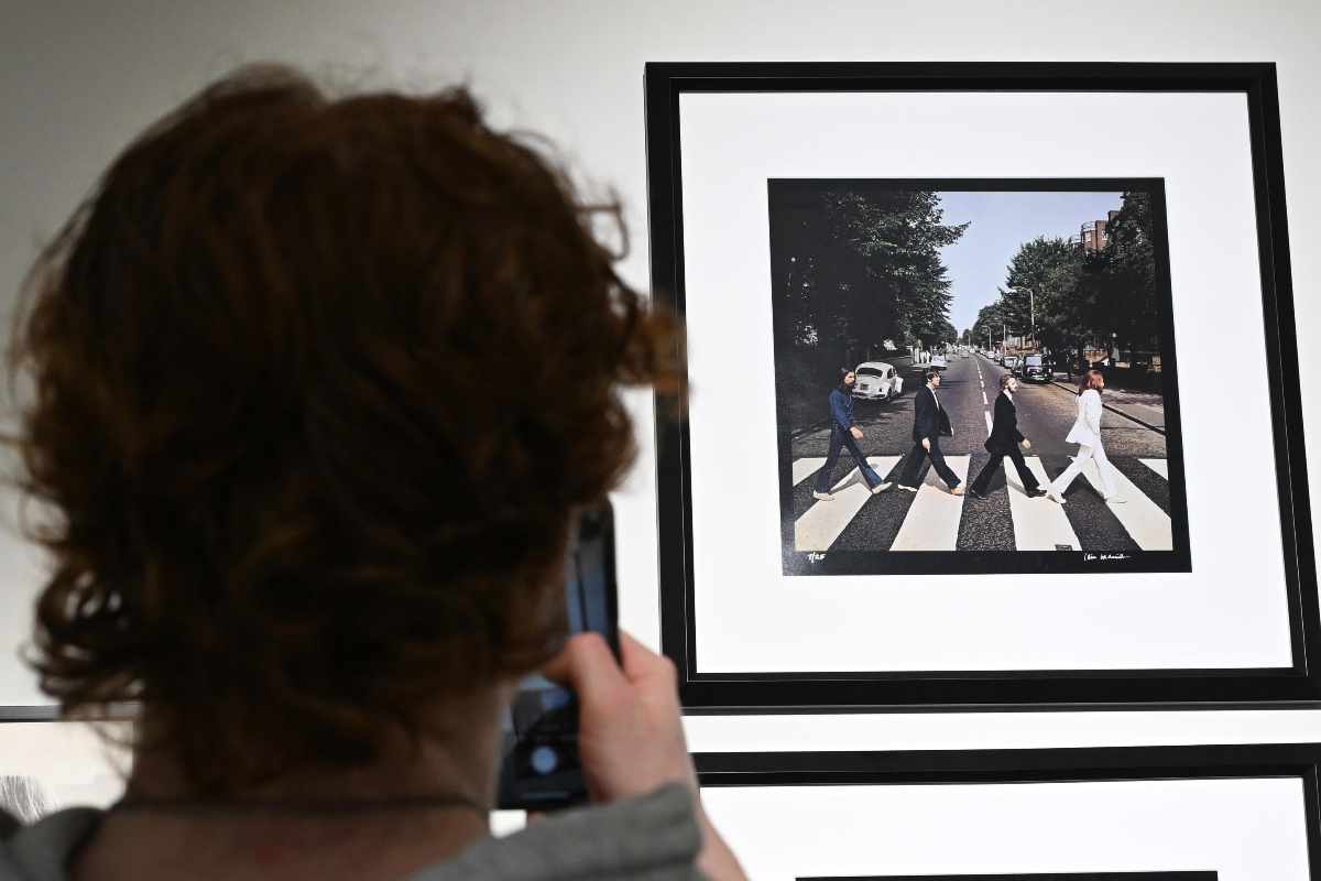 Una persona fotografa l'immagine dei Beatles mentre attraversato le strisce pedonali ad Abbey Road, a Londra