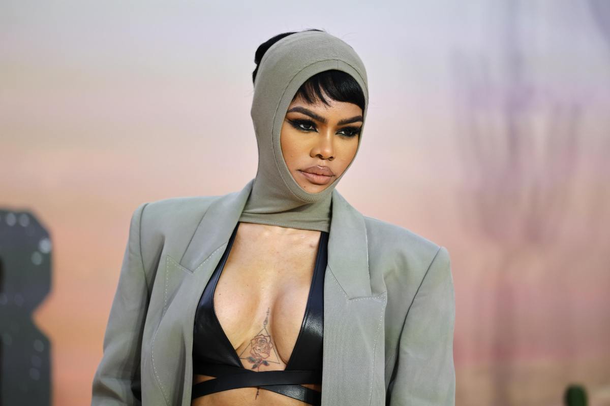 Teyana Taylor con una giacca marrone e un cappello in testa marrone che sembra essere un cappuccio. 