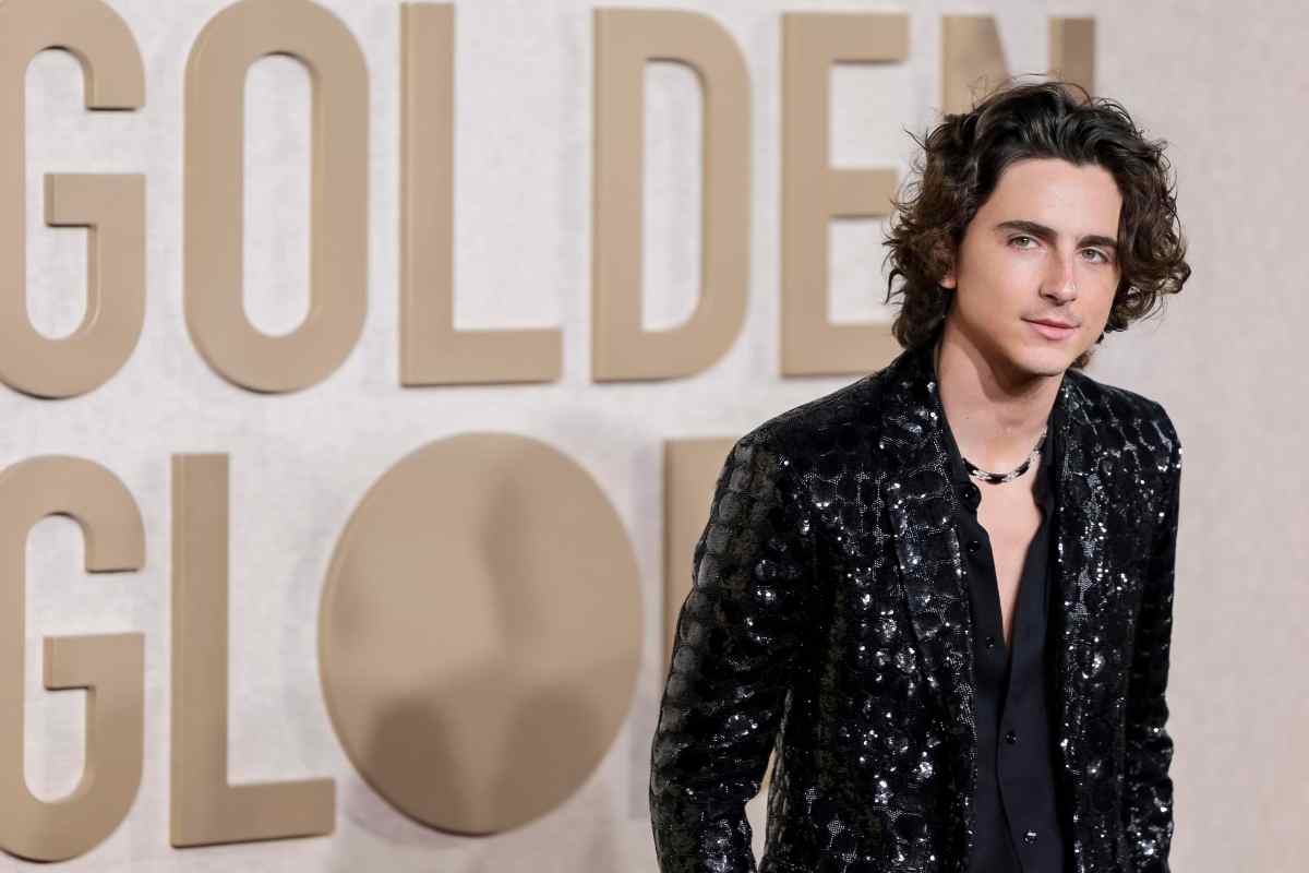 Timothee Chalamet con una giacca nera, sullo sfondo il cartello Golden Globe