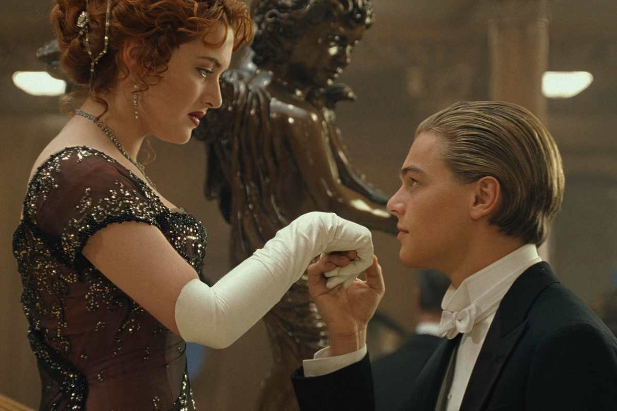 Kate Winslet e Leonardo DiCaprio in una scena di Titanic, lui inginocchiato davanti a lei le bacia la mano