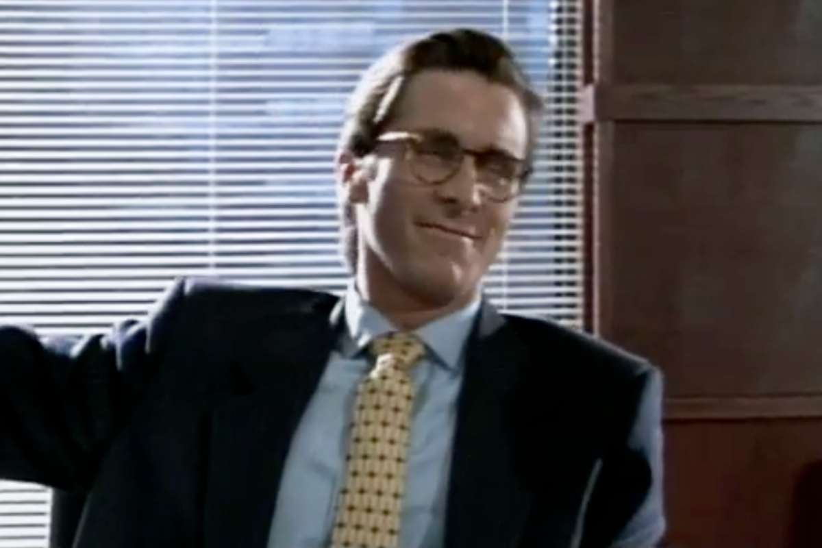 Christian Bale in giacca e cravatta e occhiali in una scena di American Psycho