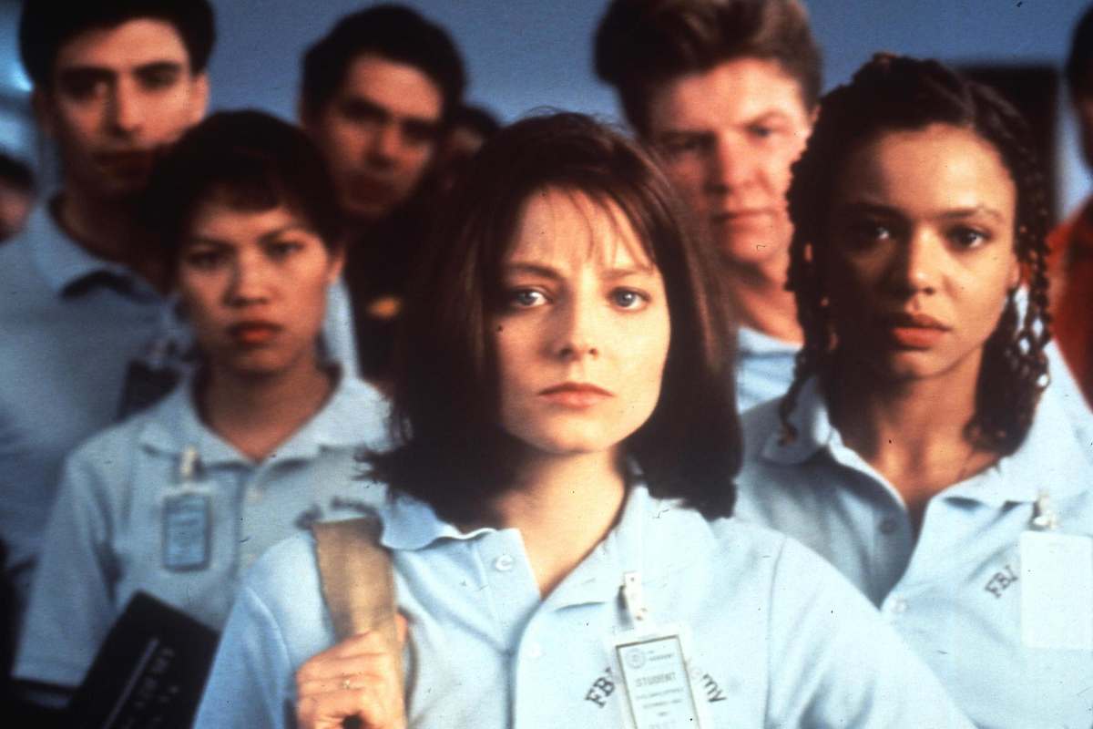 Jodie Foster in abiti da poliziotto in una scena di Hannibal Lecter intorno a lei altri poliziotti