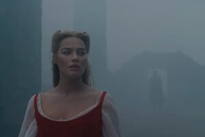 Margot Robbie in primo piano e Jacob Elordi sullo sfondo nella nebbia in una scena di 'Cime Tempestose'