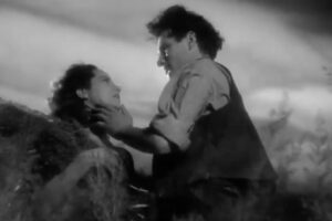 Merle Oberon e Laurence Olivier nei panni di Cathy e Heathcliff in La voce nella tempesta, Cime Tempestose. Sono uno di fronte all'altro sconvolti dal vento della brughiera, lui tocca il viso a lei.