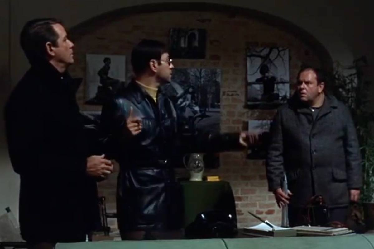 Tre uomini in una stanza in penombra si confrontano