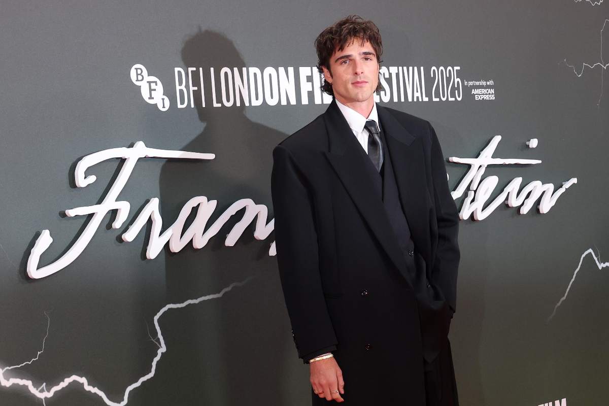 Jacob Elordi in posa davanti alla locandina del film Frankenstein