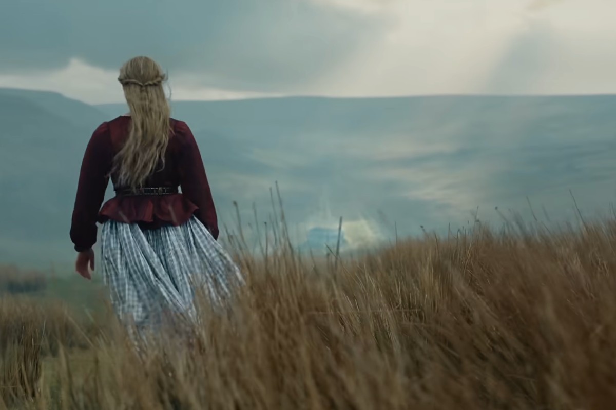 Margot Robbie di spalle cammina nella brughiera in Cime Tempestose