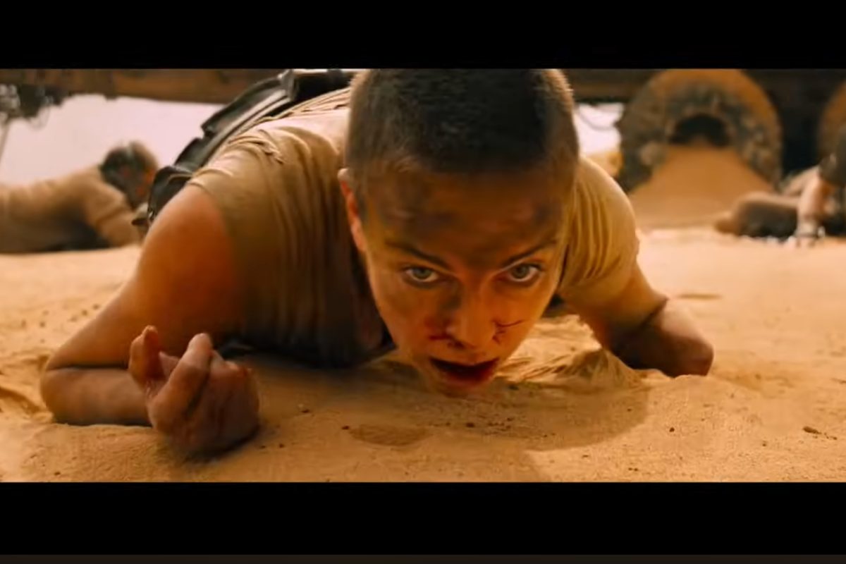 Charlize Theron sul set di Mad MAx, rasata e accovacciata a terra