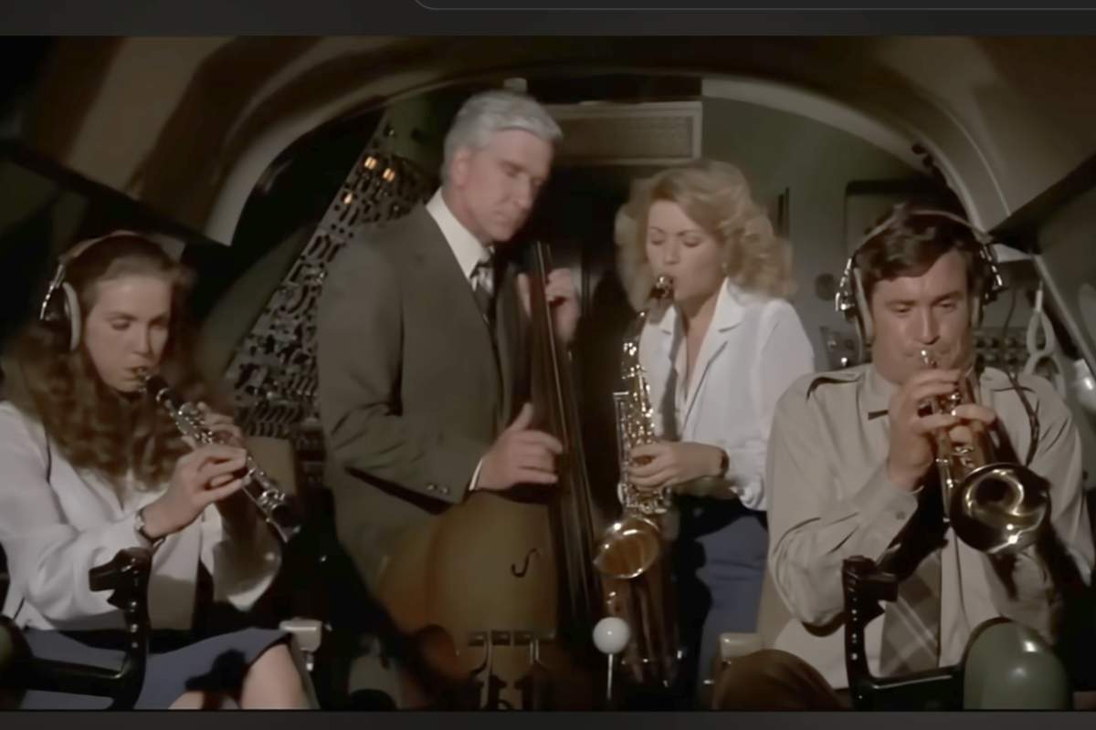 Una scena del film 'Un aereo piu' pazzo del mondo' con quattro persone che suona strumenti musicali nella cabina di pilotaggio dell'aereo