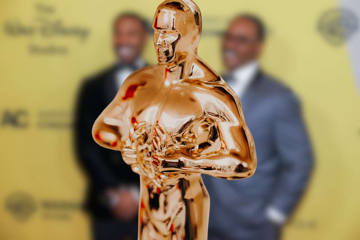 Il premio Oscar in primo piano e sullo sfondo sfocati il protagonista di Sinners e il regista